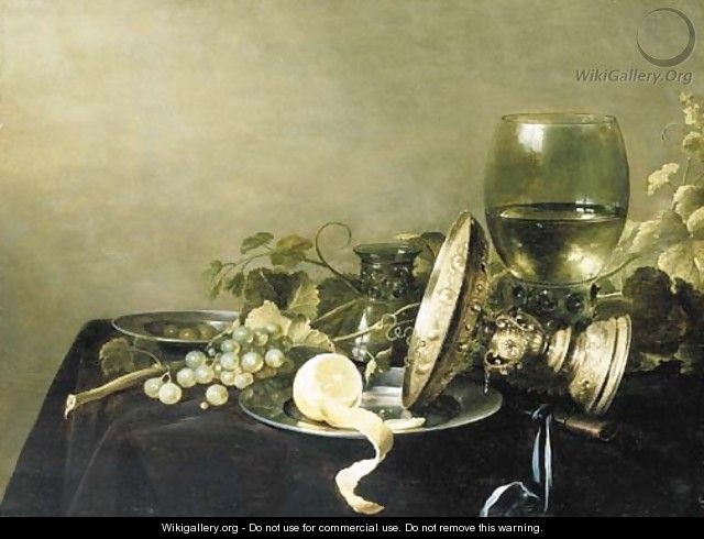 A Vanitas still life with a partially peeled lemon, grapes and olives on pewter dishes, an overturned gold tazza, an upturned glass - Pieter Claesz.