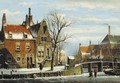 A view in a town with houses along a frozen canal, with townsfolk by a bridge - Willem Koekkoek