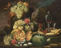 A Still Life With Grapes And Peaches In A Vase, Together With Melons, Grapes, Prunes, Peaches, Roses, Cakes And A Glass Of Red Wine On A Pewter Plate, In A Park Setting - German School
