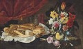 Roses, carnations, tulips and other flowers in a glass vase, with pastries and sweetmeats on a pewter platter, on a stone ledge - Giuseppe Recco