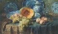 A pumpkin, peaches, and grapes in a china bowl by glasses on a draped table - Frans Mortelmans