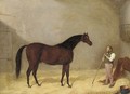A bay hunter with a groom in a stable - Martin Theodore Ward