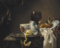 A still life of china, a goblet, fruit and a peeled lemon on a table - (after) Willem Kalf