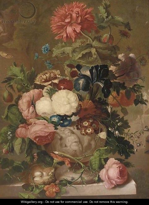 Roses, carnations and other flowers in a sculpted vase on a ledge with a bird